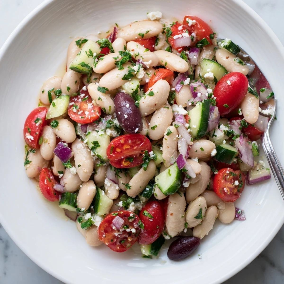 Bright and colorful white bean salad, tossed with a zesty olive oil dressing, ready to enjoy.