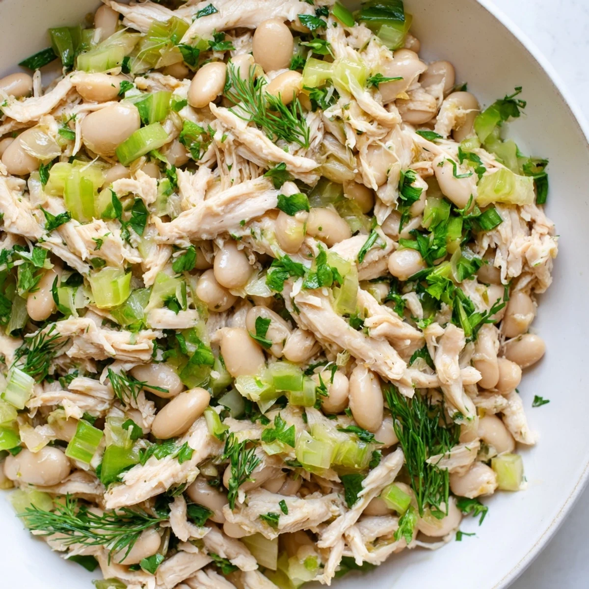 Tender shredded chicken and creamy white beans mingle with crisp celery and bright herbs in this Lemony White Bean Chicken Salad.  
