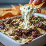 This crowd-pleasing party dip features tender shaved ribeye steak, sautéed peppers, and onions in a creamy cheese base.