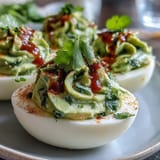 Bright green avocado filling piped into egg whites, finished with a zesty Sriracha kick.  