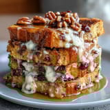 A warm Mexican bread pudding with cinnamon, piloncillo, and raisins, topped with melted cheese for a sweet and savory treat.