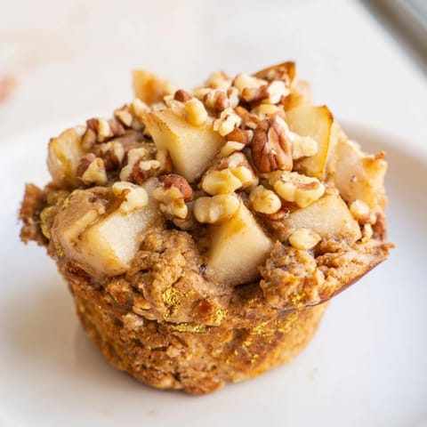 A close-up of warm, spiced pear and walnut muffins showcasing juicy pear pieces and walnuts within.