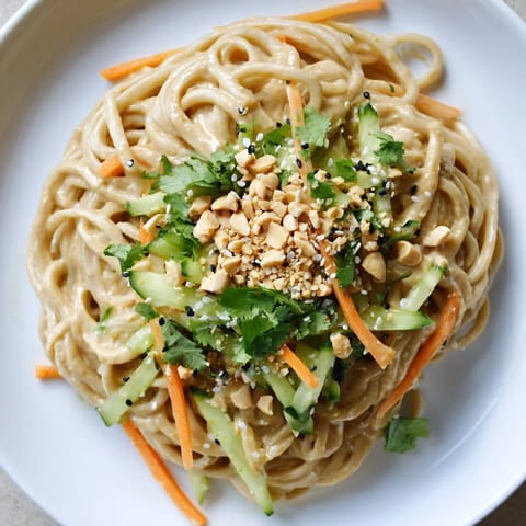 This image shows a beautifully arranged bowl of cold sesame noodles packed with fresh ingredients.