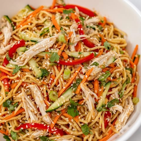 Freshly prepared Chilled Chicken Noodle Salad, showcasing tender chicken amidst vibrant sliced vegetables, perfect lunch.