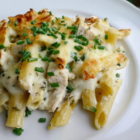 A spoon scoops a serving of the Chicken Ranch Pasta Bake, revealing layers of pasta and chicken in a rich, creamy ranch sauce.