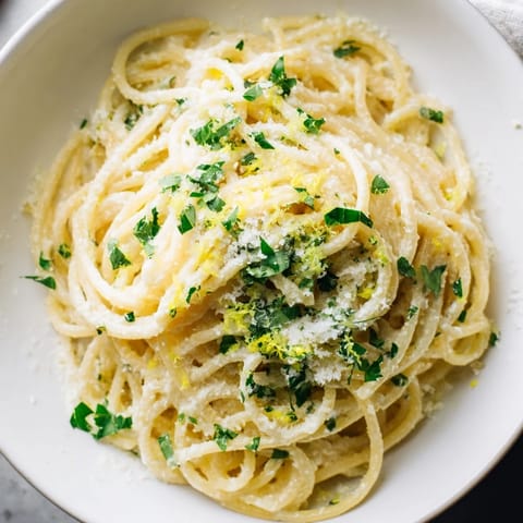 Lemon ricotta pasta served in a rustic bowl, garnished with extra lemon zest and black pepper on a wooden table.