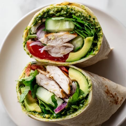 Close-up of a sliced Chimichurri Chicken Salad Wrap showing layers of juicy chicken, crisp cucumber, and tomato.