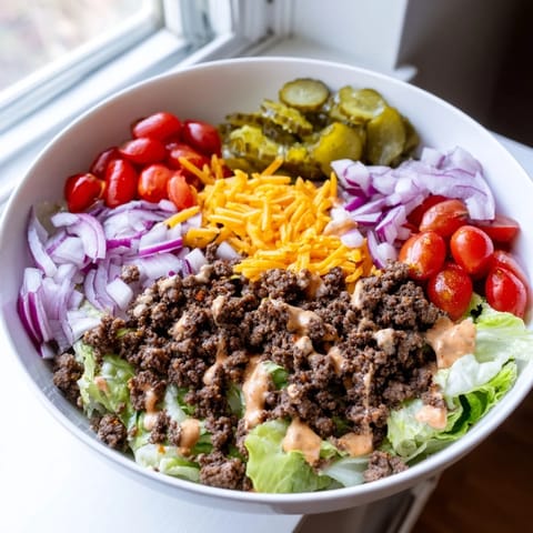 Close-up of Easy Big Mac in a Bowl with diced pickles, cherry tomatoes, and red onion, highlighting the rich, creamy dressing over the colorful salad.