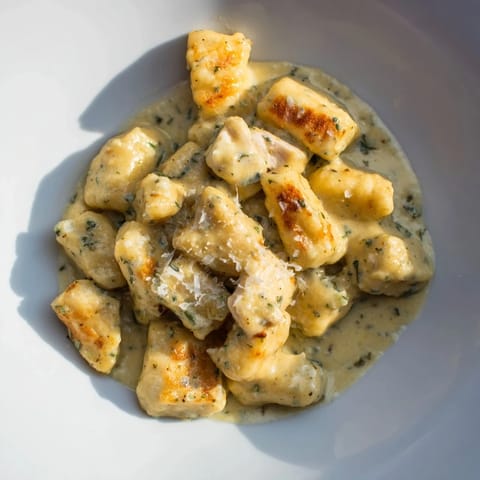 A close-up of creamy pesto gnocchi with golden pan-crisped chicken, showcasing a velvety herb sauce and a simple weeknight meal.  