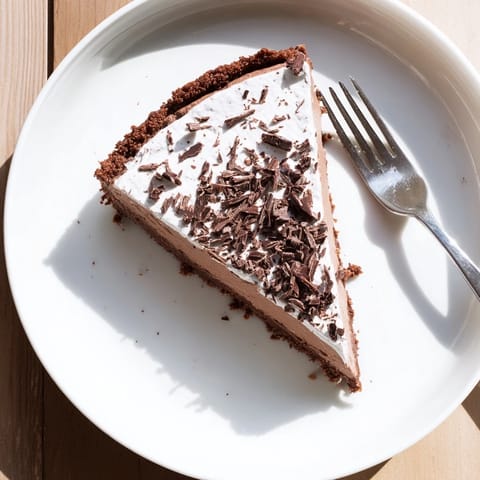 A close-up of the Lighter Chocolate Cottage Cheese Cheesecake highlights its smooth texture and slightly wobbly center, paired with fresh berries for a vibrant dessert.  