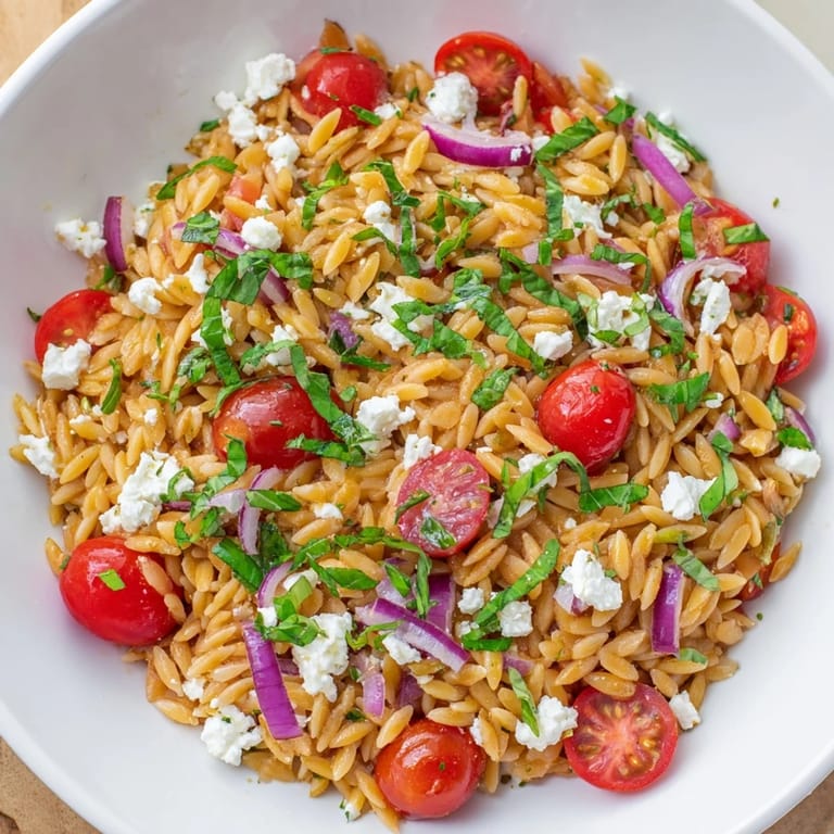 A close-up shot of the fresh Tomato Feta Orzo, showcasing the vibrant herbs and delicious dressing.
