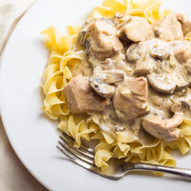 Savory Chicken and Mushroom Stroganoff simmered in a luscious sauce with tender chicken strips and earthy mushrooms atop noodles.  