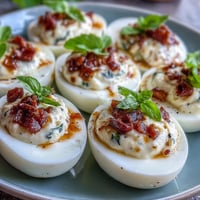 Vibrant Caprese Deviled Eggs topped with fresh basil oil and tomato.